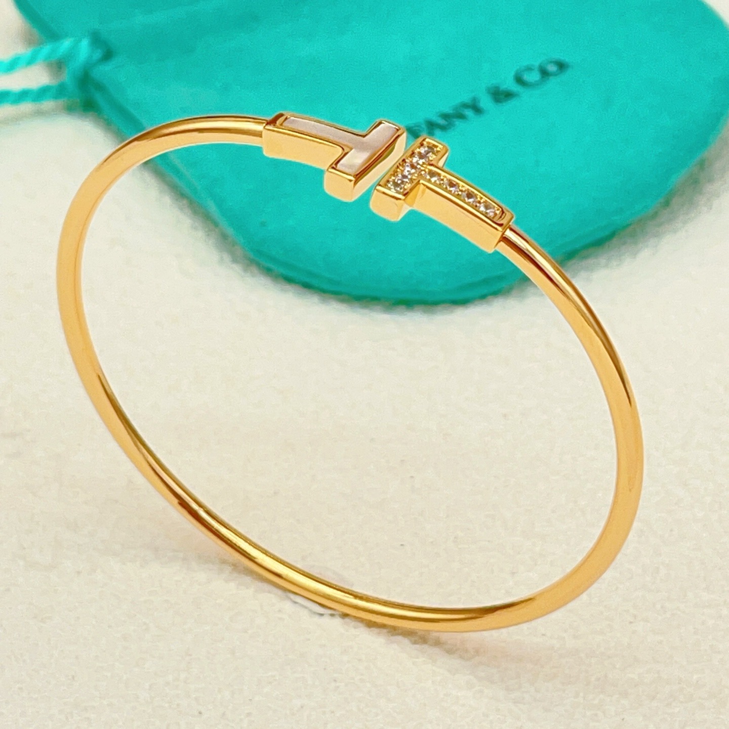 Tiffany Co T Wire bracelet yellow gold metal with white mother-of-pearl and clear diamond accents 17cm inner circumference