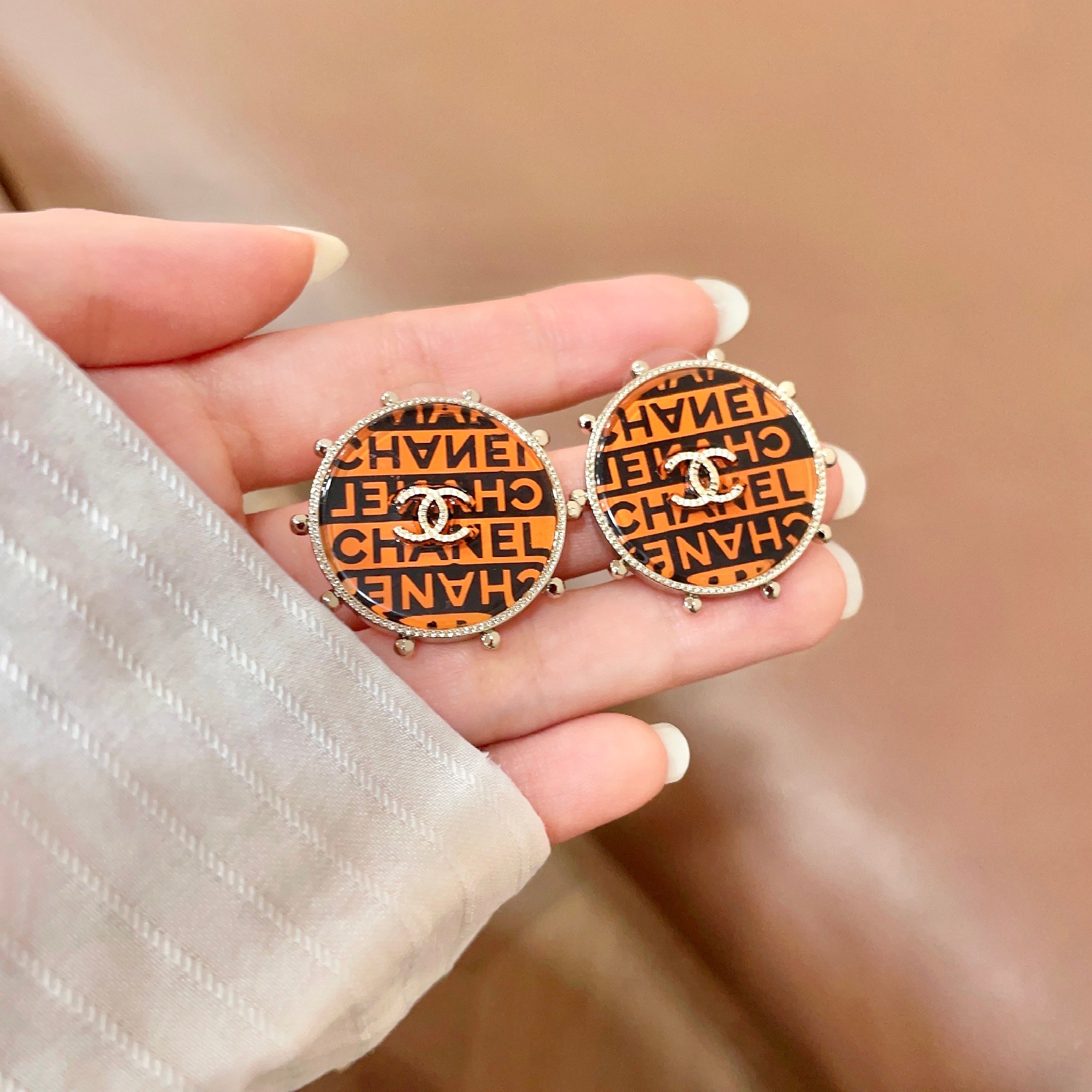 Chanel CC Logo Round Printed Stud Earrings earrings Gold-tone metal with clear crystal accents orange and black enamel printed with Chanel text 2 5cm diameter
