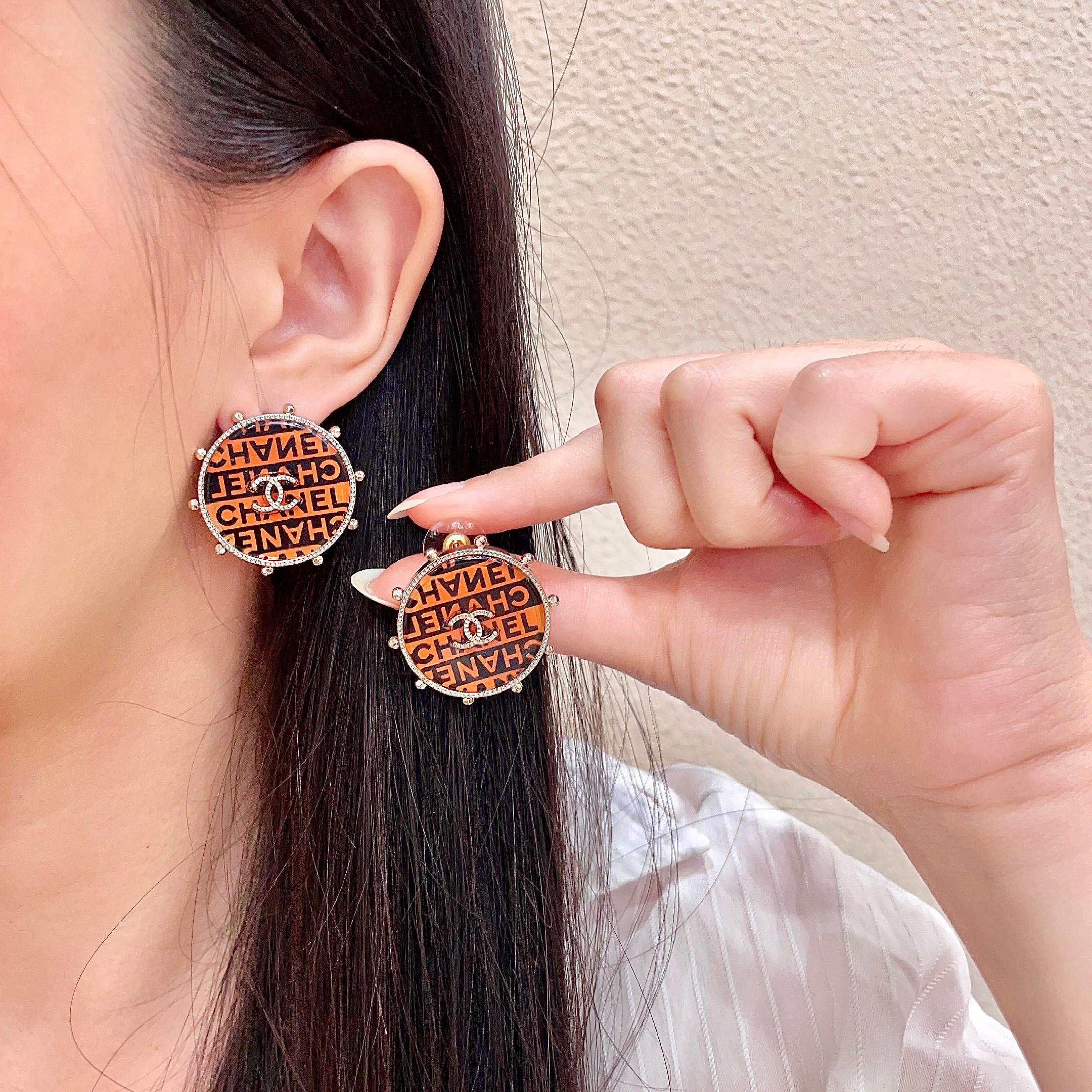 Chanel CC Logo Round Printed Stud Earrings earrings Gold-tone metal with clear crystal accents orange and black enamel printed with Chanel text 2 5cm diameter