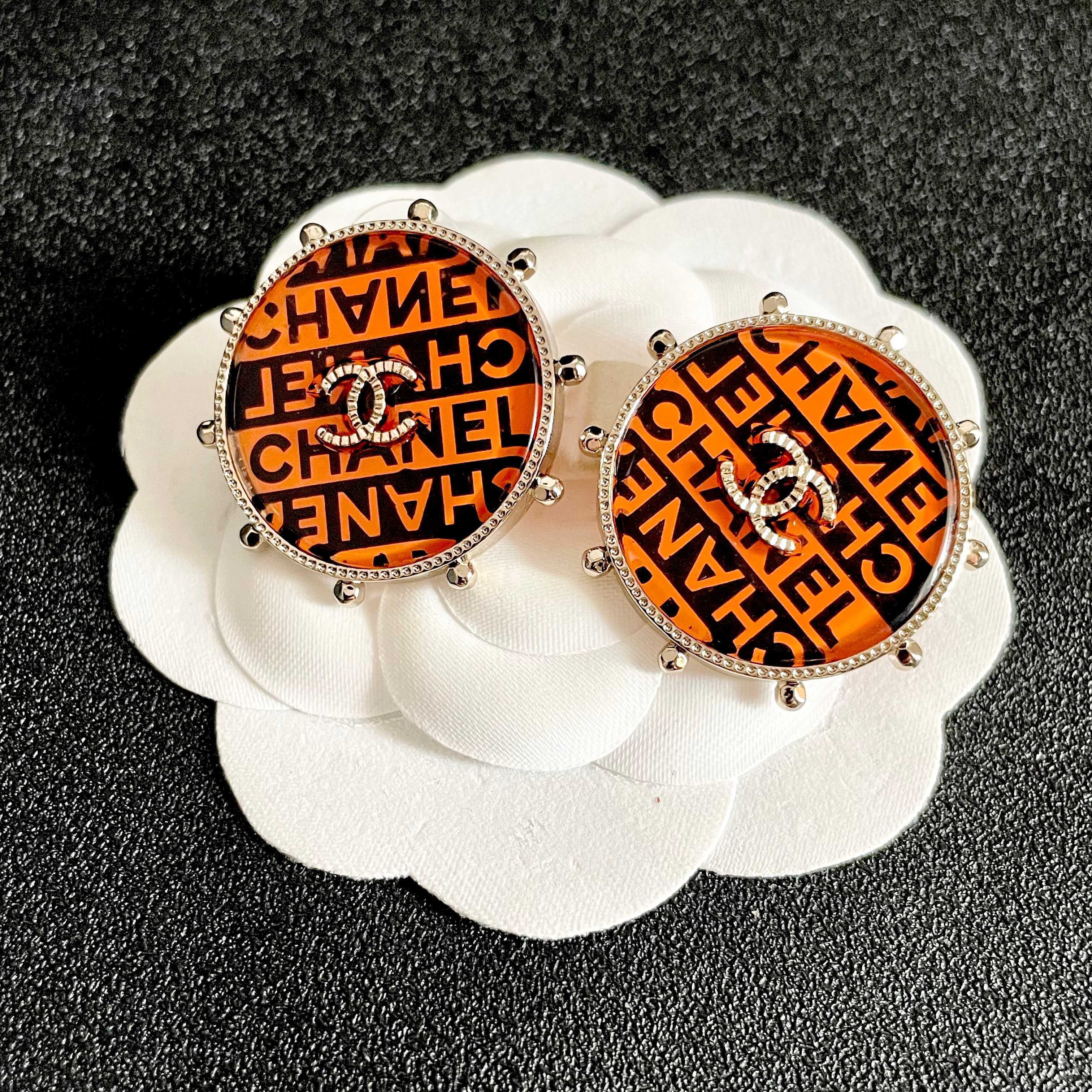 Chanel CC Logo Round Printed Stud Earrings earrings Gold-tone metal with clear crystal accents orange and black enamel printed with Chanel text 2 5cm diameter