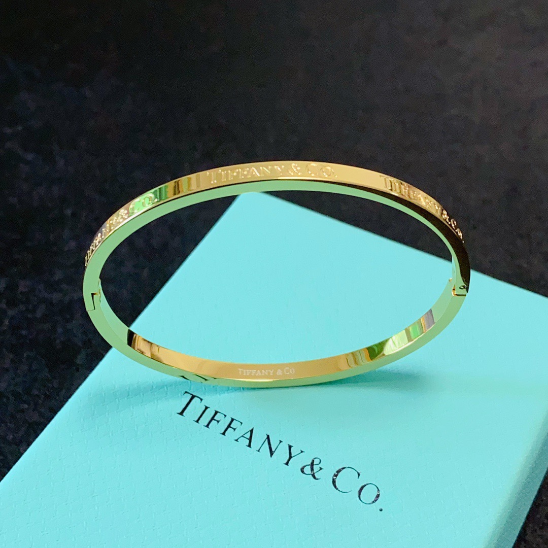 Tiffany Co Tiffany Logo Engraved Hinged Bangle bracelet Polished gold-tone metal no accent stones 17cm inner circumference