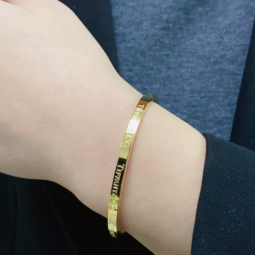 Tiffany Co Tiffany Logo Engraved Hinged Bangle bracelet Polished gold-tone metal no accent stones 17cm inner circumference