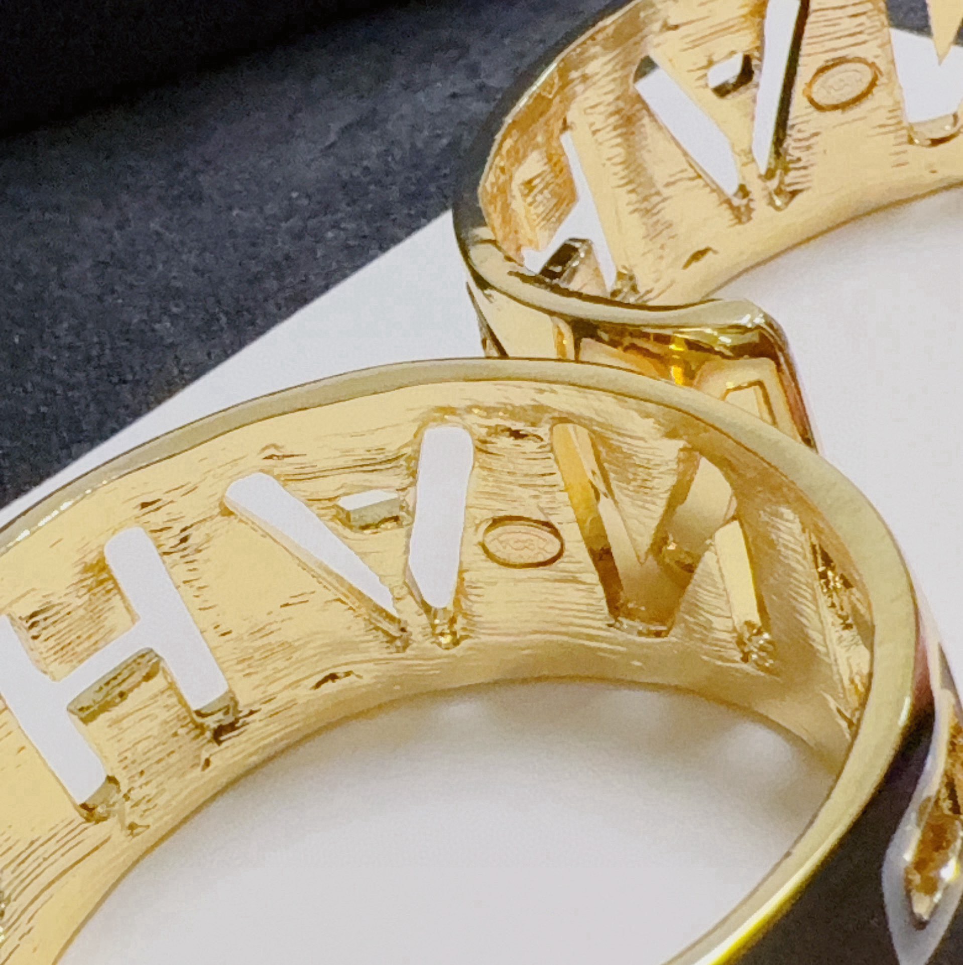 Chanel CHANEL Logo Cutout Wide Cuff bracelet Gold-tone metal with white enamel outlined cutout CHANEL lettering One Size adjustable open cuff fits 15-18cm wrist circumference