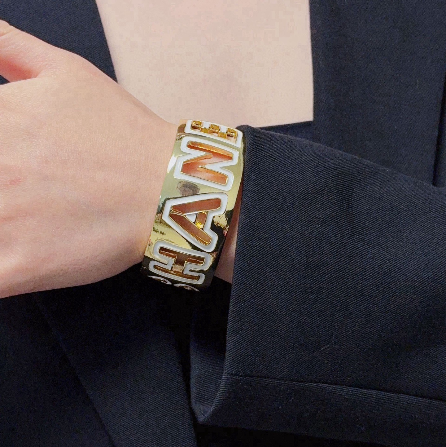 Chanel CHANEL Logo Cutout Wide Cuff bracelet Gold-tone metal with white enamel outlined cutout CHANEL lettering One Size adjustable open cuff fits 15-18cm wrist circumference