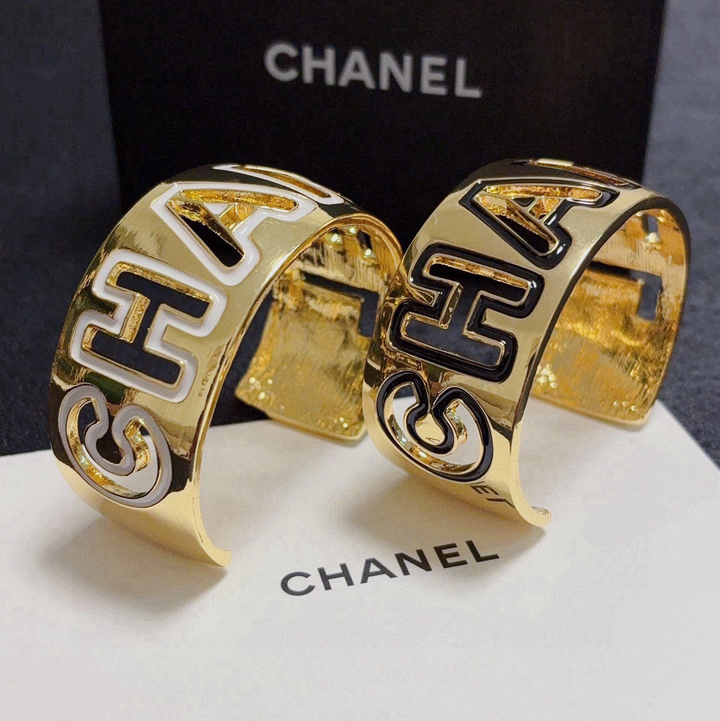 Chanel CHANEL Logo Cutout Wide Cuff bracelet Gold-tone metal with white enamel outlined cutout CHANEL lettering One Size adjustable open cuff fits 15-18cm wrist circumference