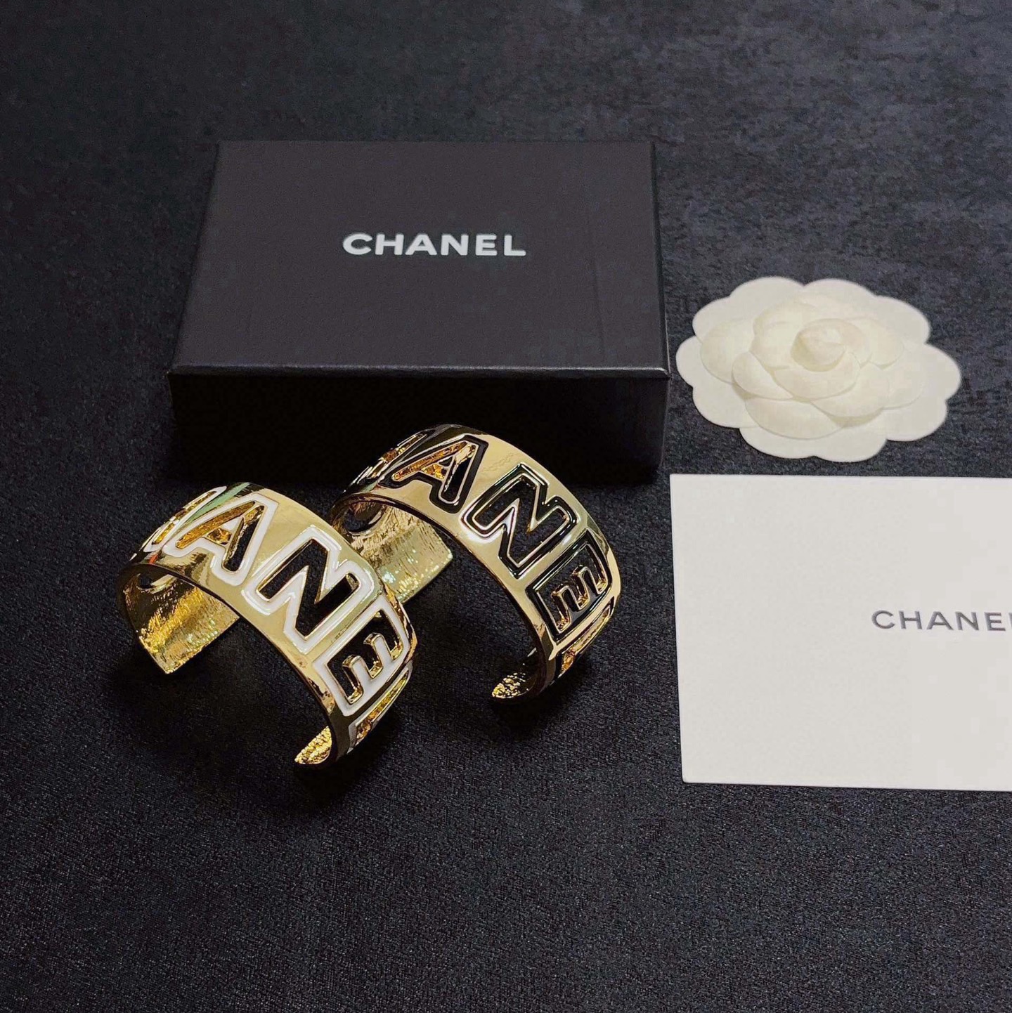 Chanel CHANEL Logo Cutout Wide Cuff bracelet Gold-tone metal with white enamel outlined cutout CHANEL lettering One Size adjustable open cuff fits 15-18cm wrist circumference